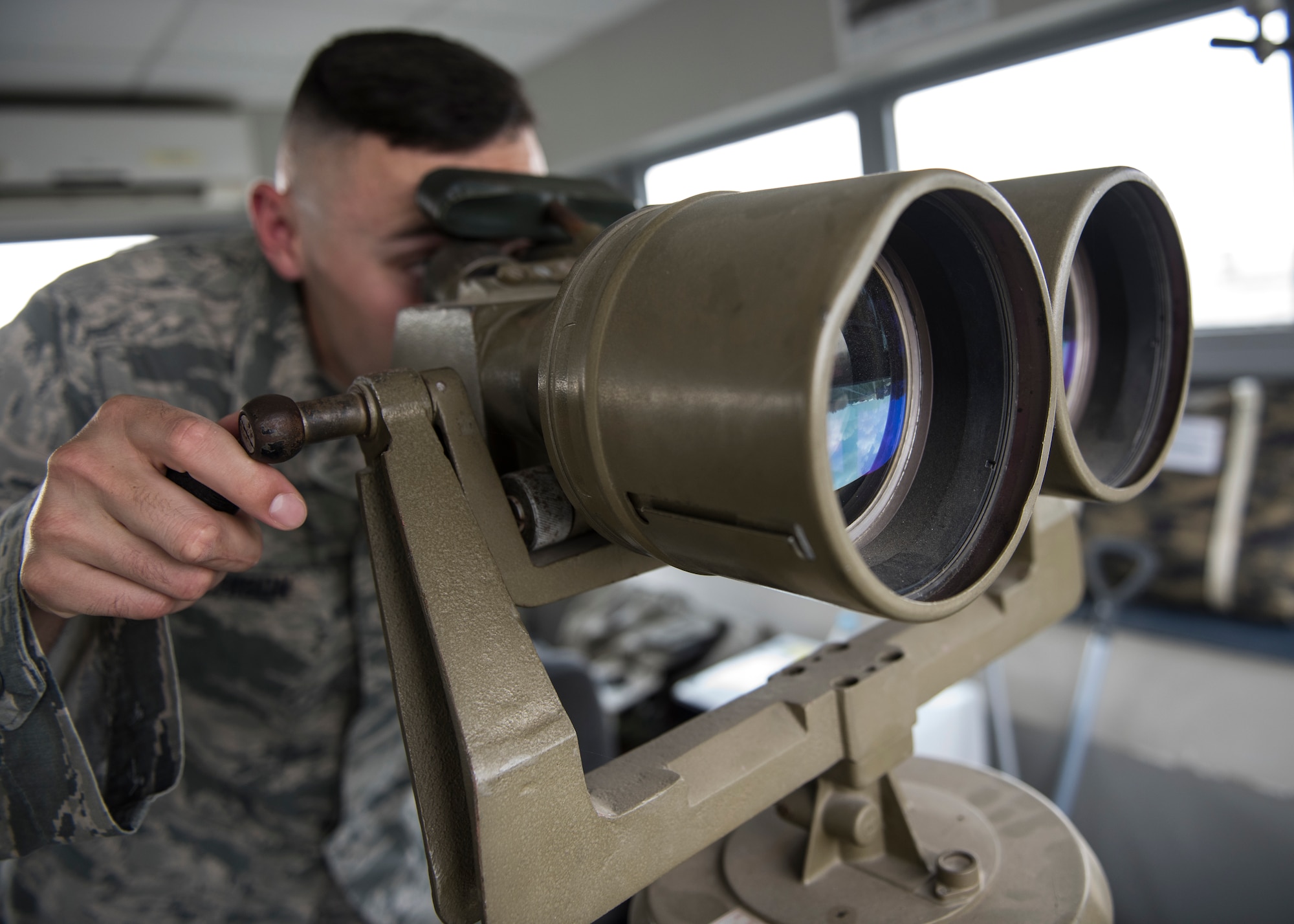 U.S. Air Force Staff Sgt. Cody Hutchison, 39th Security Forces Squadron, looks through binoculars on top of a watch tower at Incirlik Air Base, Turkey, June 21, 2018.