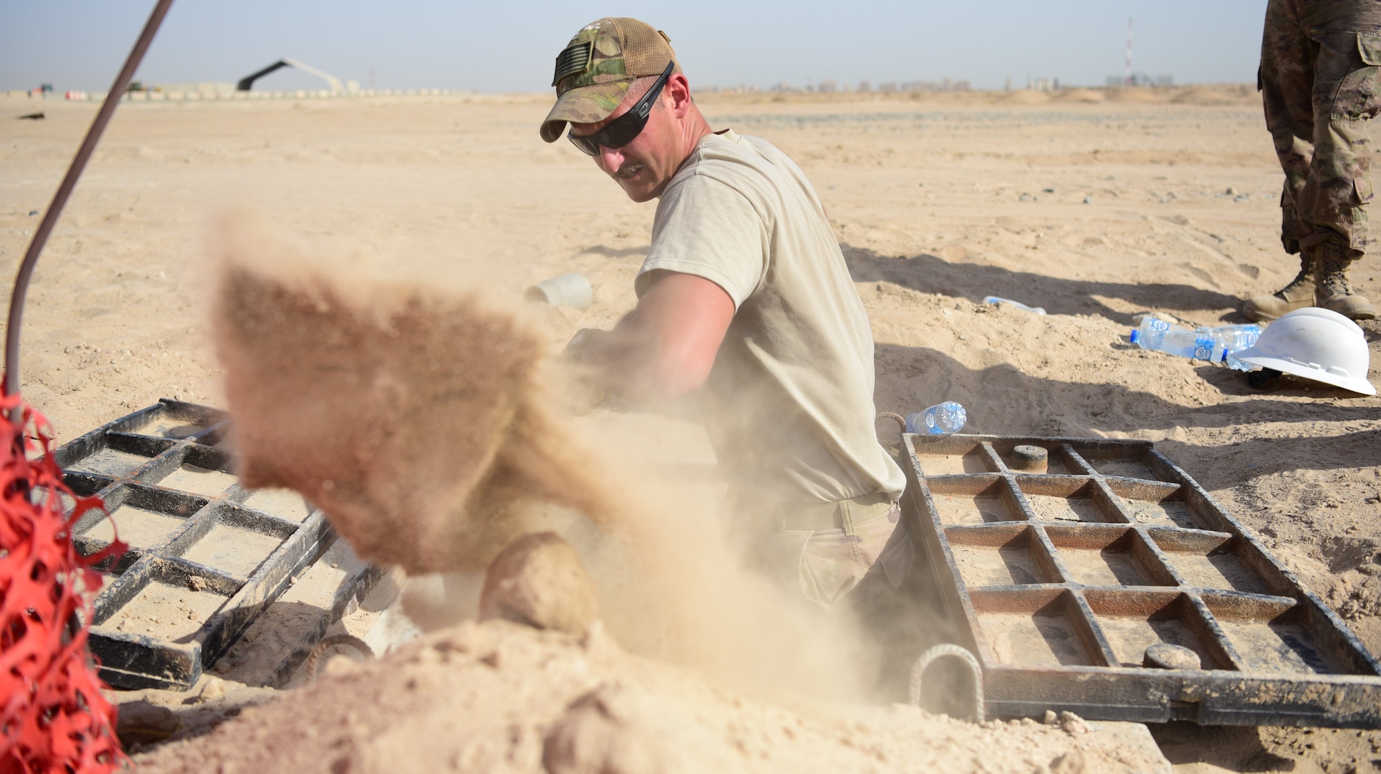 Senior Airman Austin Stimmel, 379th Expeditionary Civil Engineer Squadron cable and antenna systems technician, shovels dirt from a cable storage area at Cargo City, located at Abdullah Al Mubarak Air Base, Kuwait, June 25, 2018. Stimmel and his fellow Airmen are installing communications lines for the new operating location, slated to open later this year. (U.S. Air Force photo by Staff Sgt. Christopher Stoltz)