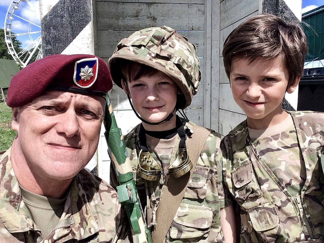 A soldier takes a photo with two French boys dressed as soldiers.