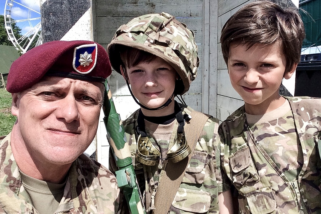 An Army officer takes a selfie with two boys dressed as soldiers.