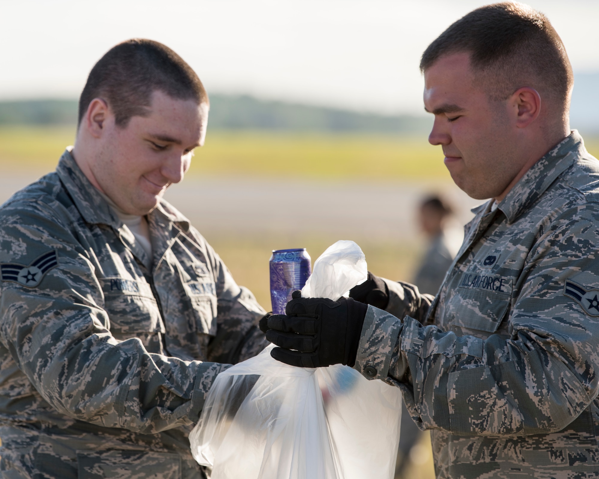 Senior Airman Cody Powers and Airman 1st Class Tyler Parnell, both 3rd Munitions Squadron muntions systems crew chiefs, pick up trash during a foreign object and debris walk at Joint Base Elmendorf-Richardson, Alaska, July 2, 2018. The JBER Airmen conducted the FOD walk after the Arctic Thunder Open House to remove debris that could damage aircraft and hinder mission readiness.