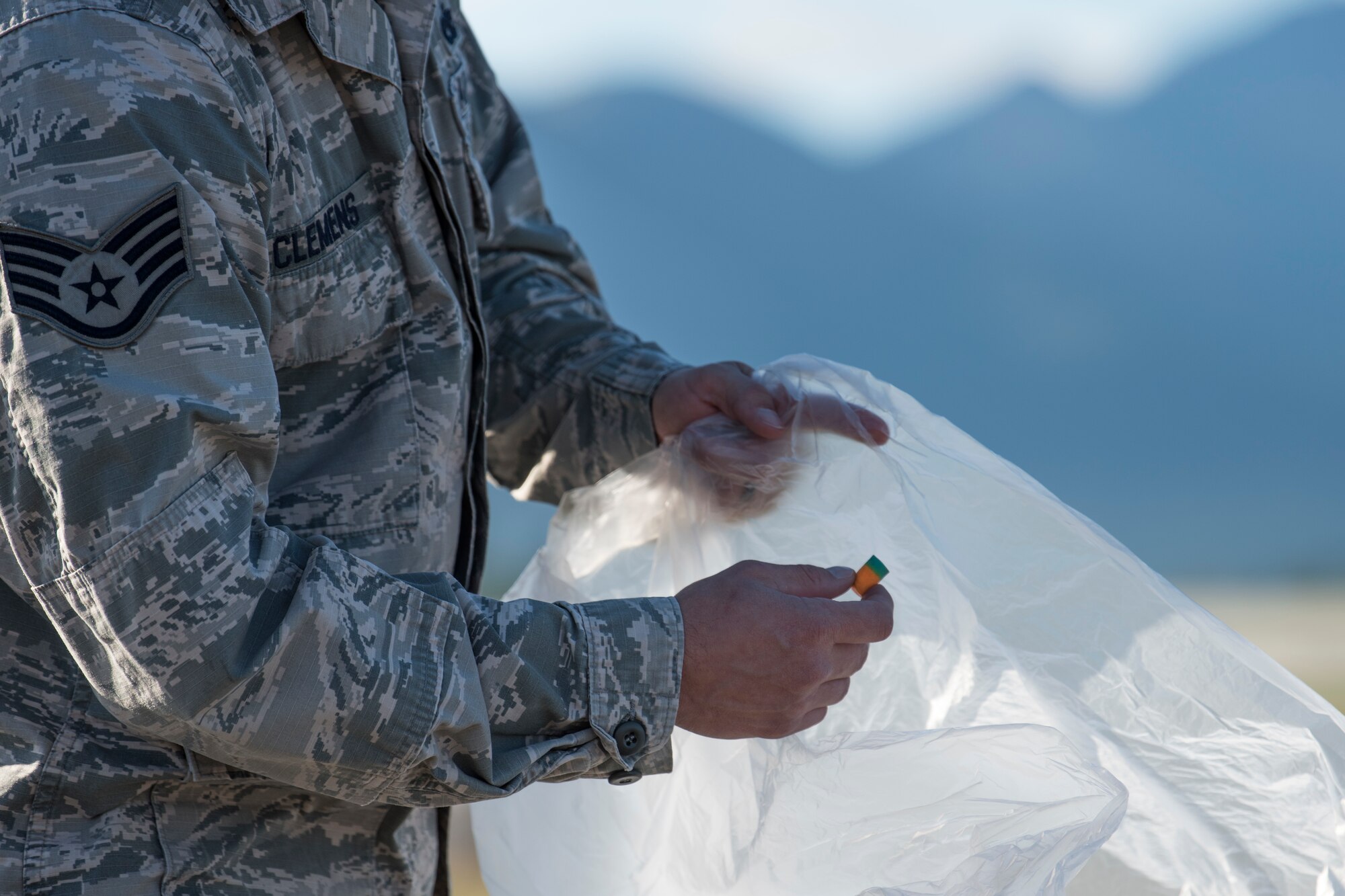 Staff Sgt. Andrew Clemens, a 3rd Munitions Squadron muntions systems crew chief, picks up a discarded ear plug during a foreign object and debris walk at Joint Base Elmendorf-Richardson, Alaska, July 2, 2018. The JBER Airmen conducted the FOD walk after the Arctic Thunder Open House to remove debris that could damage aircraft and hinder mission readiness.