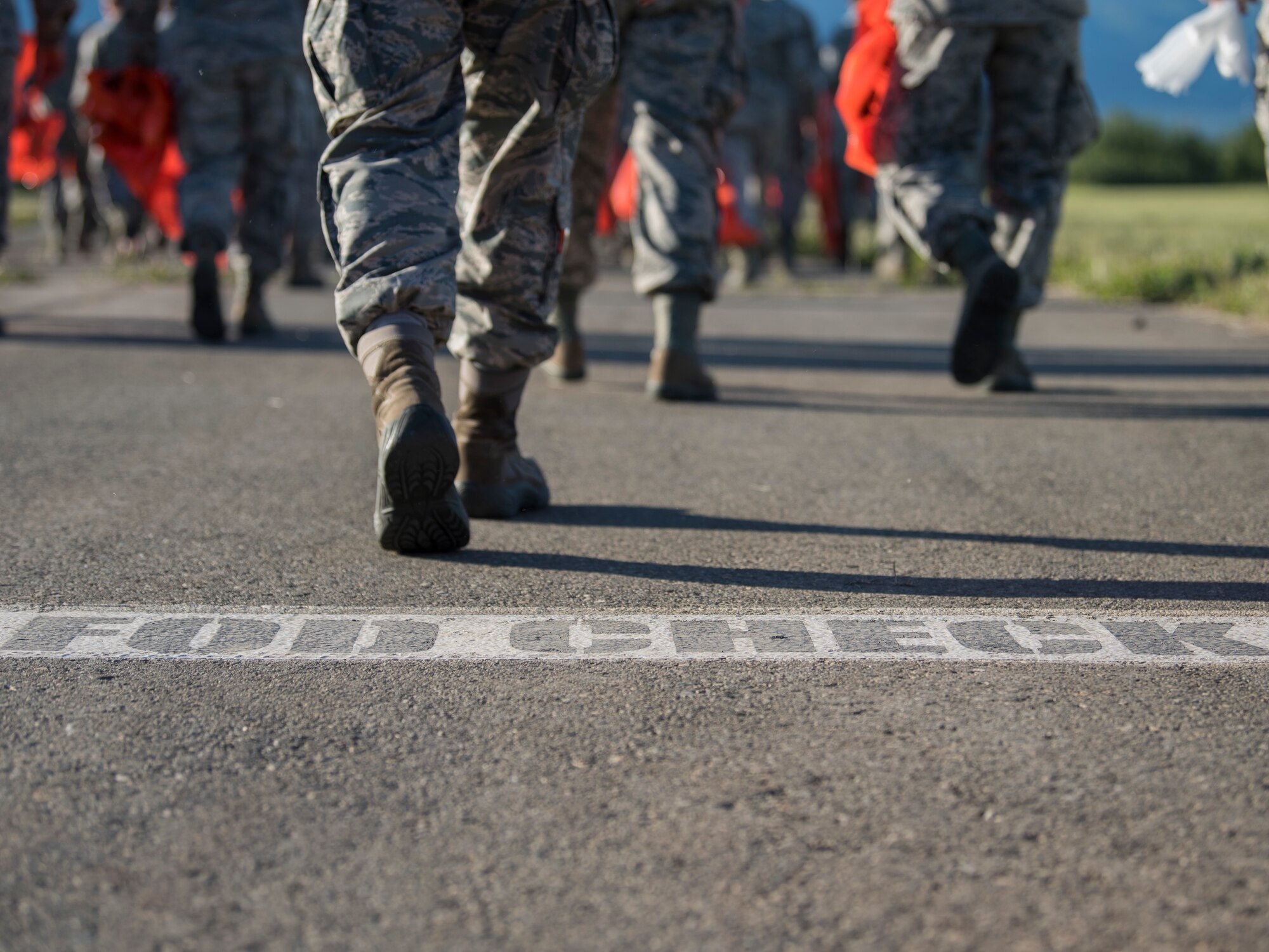 Joint Base Elmendorf-Richardson Airmen walk toward the flight line as they prepare to conduct a foreign object and debris walk at JBER, Alaska, July 2, 2018. The Airmen conducted the FOD walk after the Arctic Thunder Open House to remove debris that could damage aircraft and hinder mission readiness.