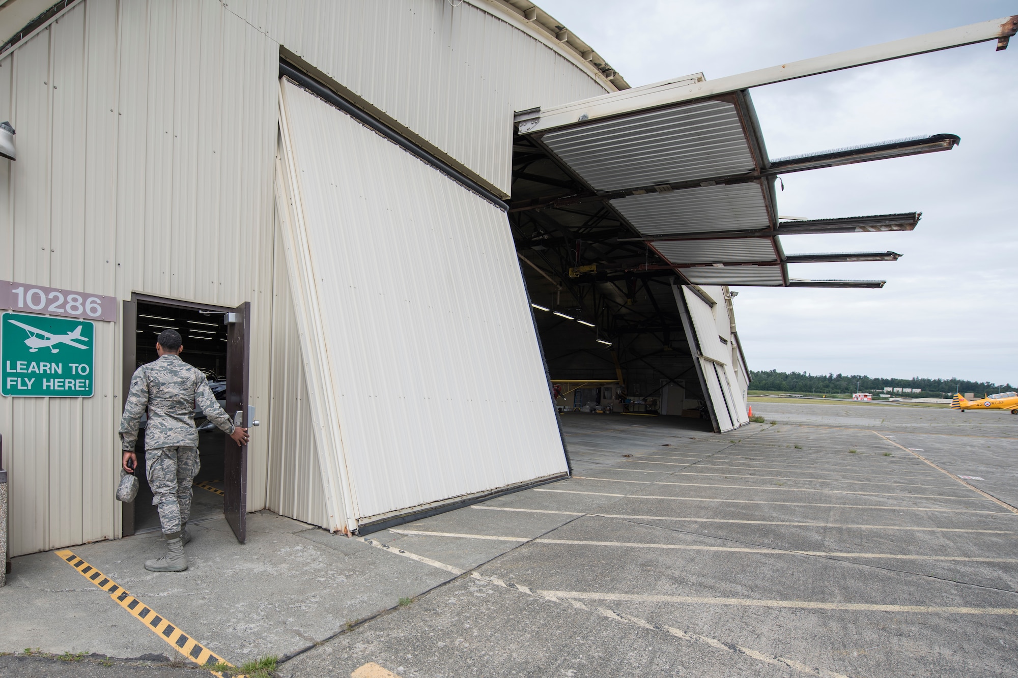 Airman 1st Class Ty Wilkerson, a 517th Airlift Squadron aviation resource manager walks through the door of the Elmendorf Aero Club hangar at Joint Base Elmendorf-Richardson, Alaska, June 28, 2018. Wilkerson is a single Airman getting more information about the introductory flight offered and checking into the flight instruction programs the club offers.