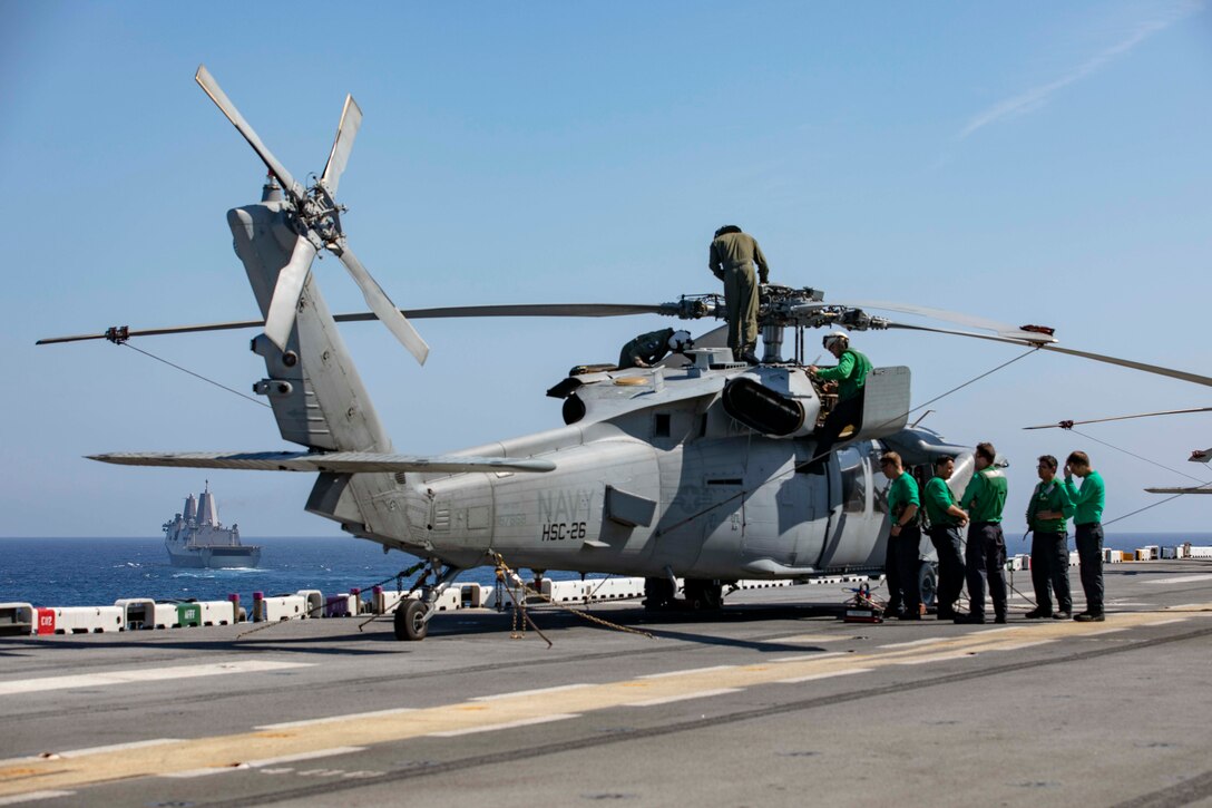 Sailors perform pre-flight checks on a MH-60S Seahawk helicopter.