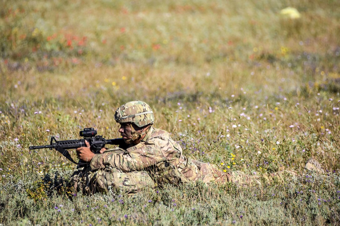 A paratrooper takes aim while providing perimeter security for his team.