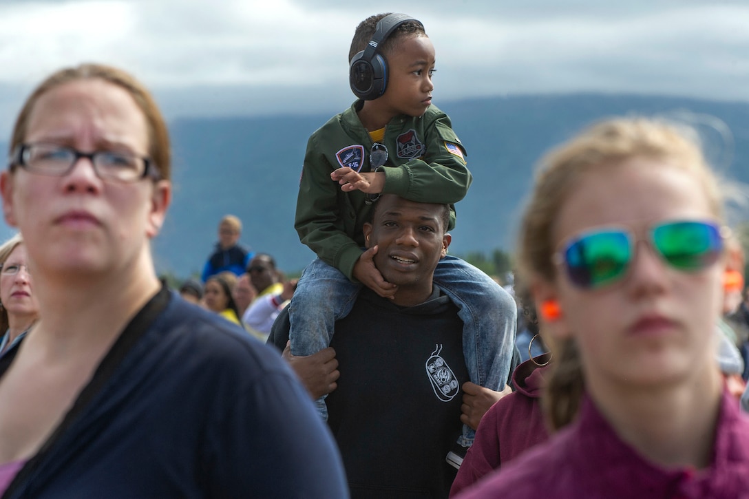 An airman holds his son on his shoulders to watch a demonstration.