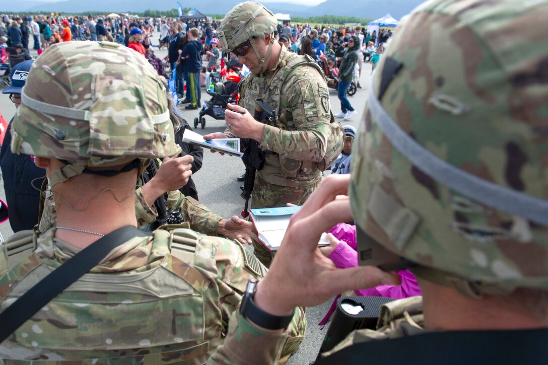 A soldier autographs a program for a spectator after a demonstration.