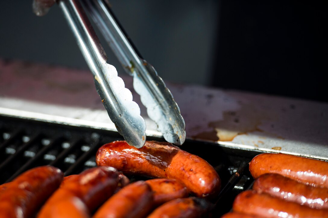 A volunteer grills hot dogs during the Patriot Festival, July 3, 2018, at Moody Air Force Base, Ga. Team Moody hosted the free event to allow Airmen and their families an opportunity to take some time away from the mission and enjoy a Fourth of July experience. The event consisted of live music, food trucks, family fun and a firework show. (U.S. Air Force photo by Airman 1st Class Erick Requadt)