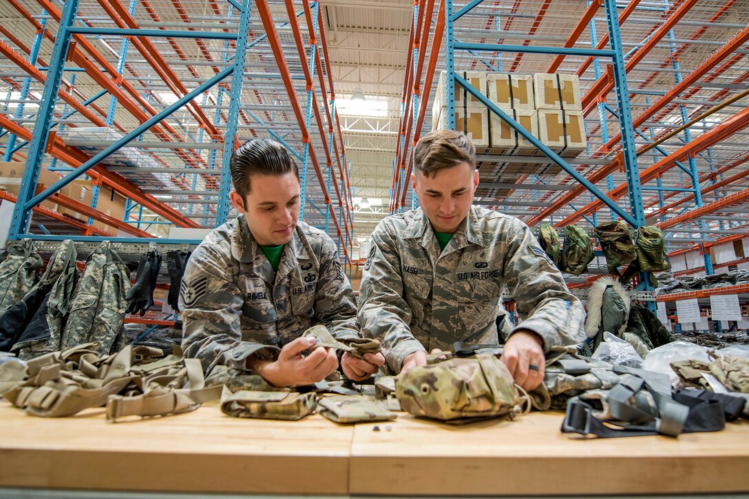 Two airmen inspect equipment on a table.