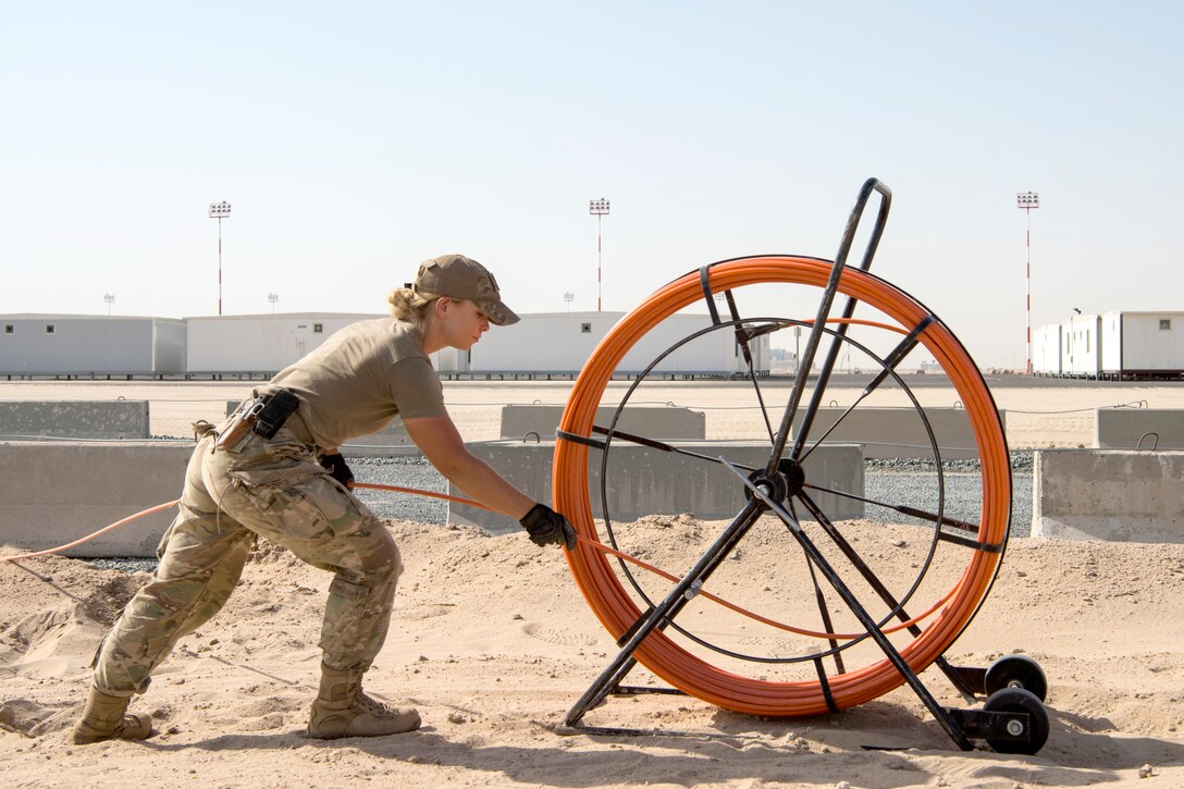 An airman winds line onto a large spool.