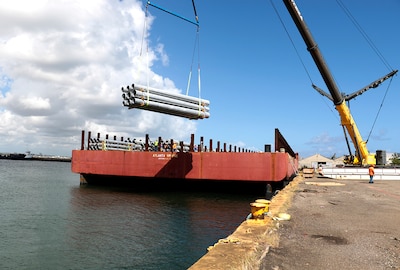 Federal Emergency Management Agency contractors unload utility poles from the barge Atlanta Bridge at Port of San Juan, Puerto Rico.