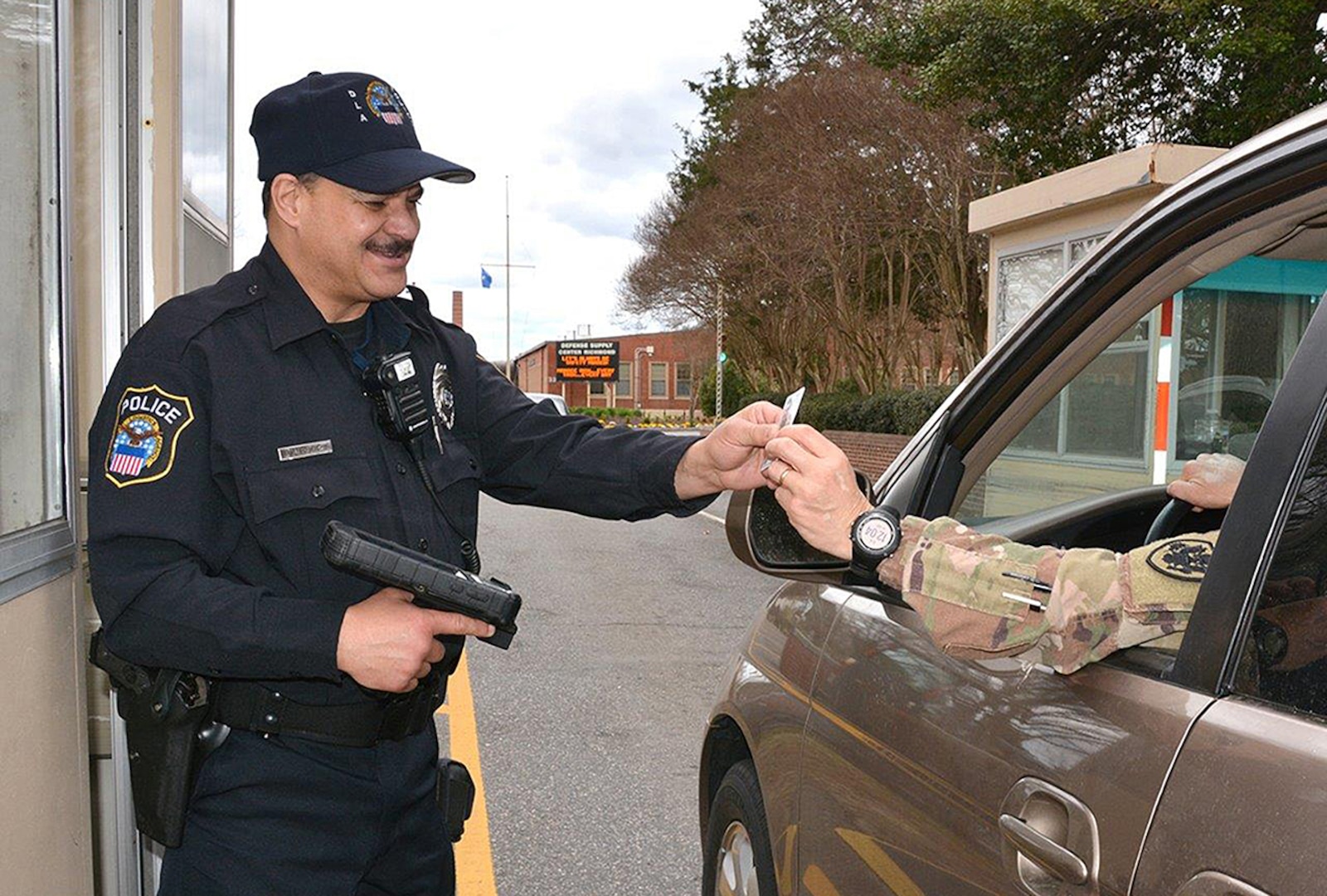 DLA Installation Operations Police Officer Kevin Buhler checks an identification card at the gate of Defense Supply Center Richmond, Virginia, using the Defense Biometric Identification System.