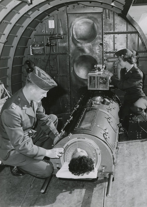 The “flying lung” designed at the U.S. Air Force School of Aviation Medicine in 1952. A flight nurse adjusts and prepares to disconnect the battery used during transport from the hospital to the aircraft, January 29, 1953. Once aboard, the pressure pump plugged directly into the plane’s electrical system to power the flying lung during flight. (Photo courtesy of National Archives and Records Administration)