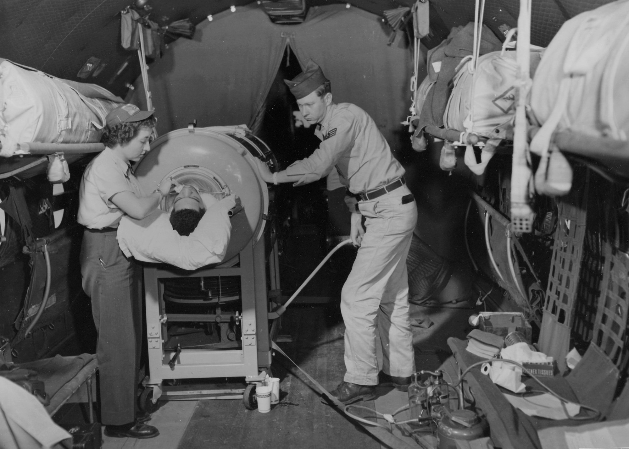 Airman 3rd Class Warren Beatty in a “flying lung” aboard a 374th Troop Carrier Wing C-54 Skymaster, cared for by 1st Lt. Shirley C. Warren, a flight nurse, and Staff Sgt. Lawrence Kiger, a medical technician, en route from Korea to Japan, July 23, 1953. Beatty, stricken with a lung ailment while stationed at Inchon Harbor, Korea, was the first iron lung patient to receive an airlift from the Korean theater. (Photo courtesy of National Archives and Records Administration)