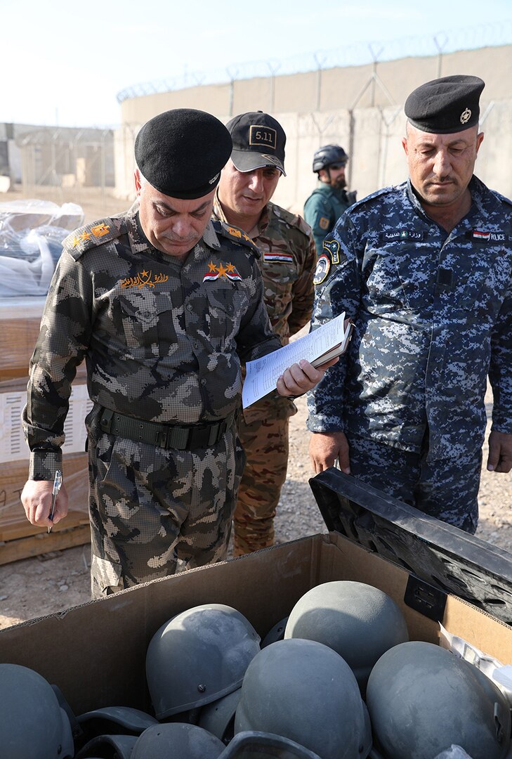 Members of the Iraqi army and police look at ballistic helmets in a container during the divestment of organizational clothing and individual equipment to the Iraqi army and police at the Besmaya Range Complex, Iraq.