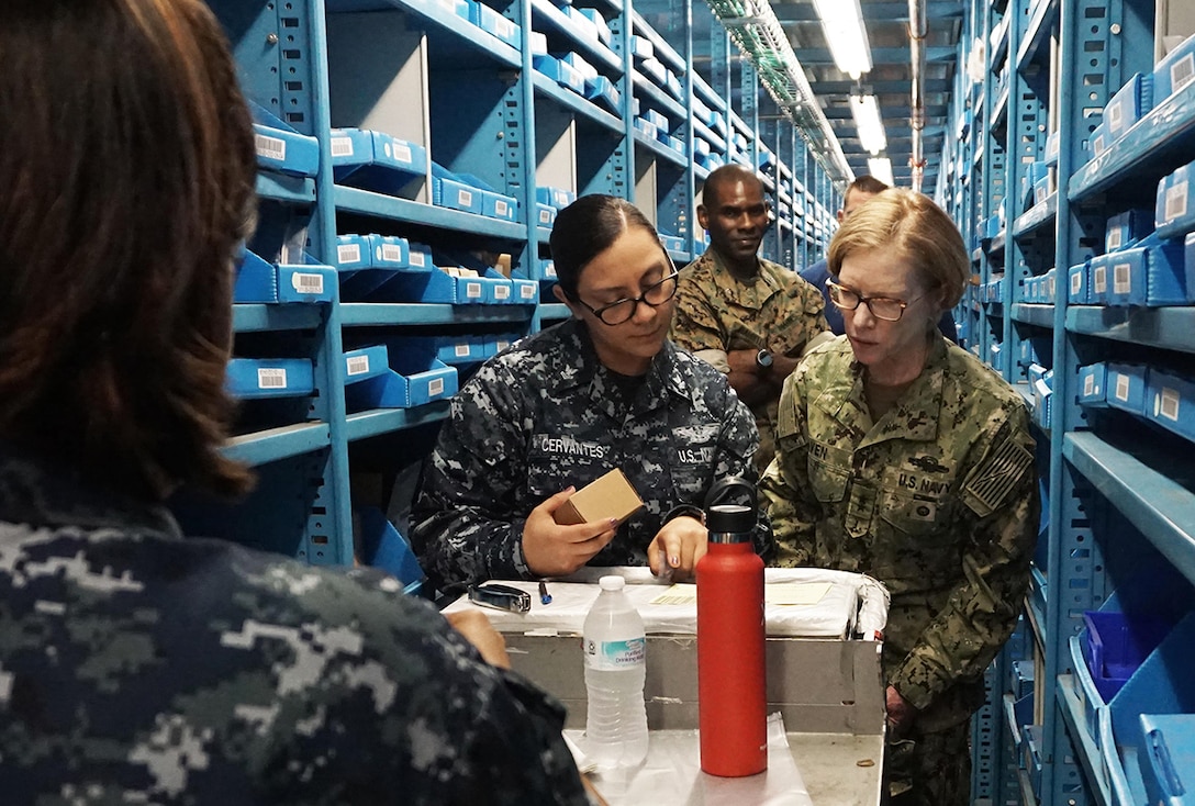 Navy Rear Adm. Deborah Haven, director of the DLA Joint Reserve Force, observes the process of picking bin materiel from Navy Petty Officer 2nd Class Elsa Cervantes.