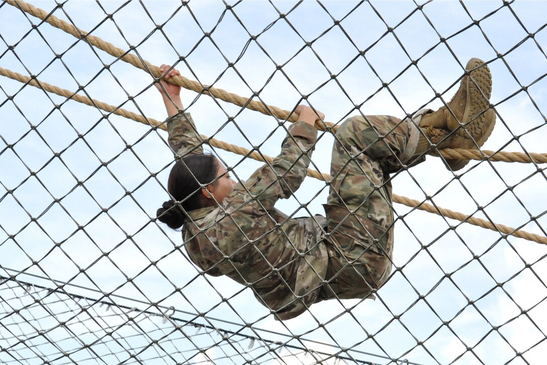 A soldier climbs on a rope.