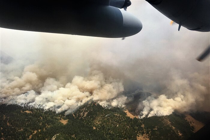 An airplane flies over a fire.