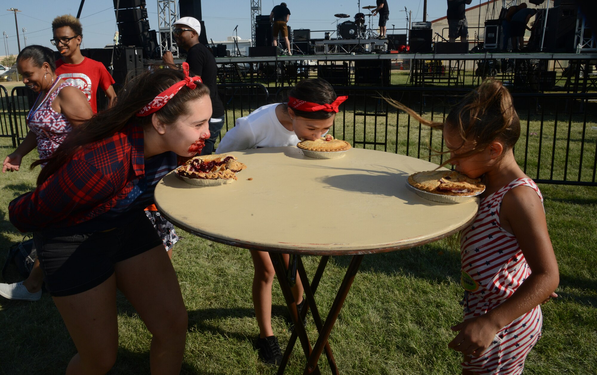 Pie eating contestants eat their way to the end of a pie for a prize at the Summer Bash at Wings Field, July 4. Each pie had a prize such as a gift card at the bottom of the pie tin. (U.S. Air Force photo by Laura Motes)