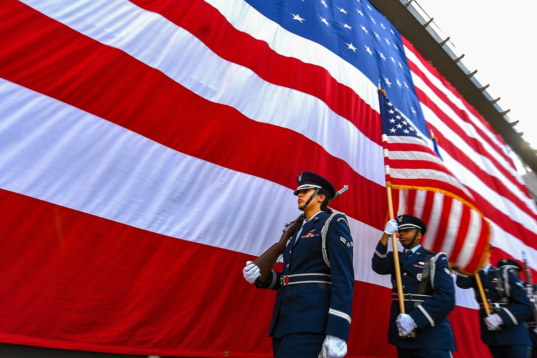Airmen line up next to an American Flag.