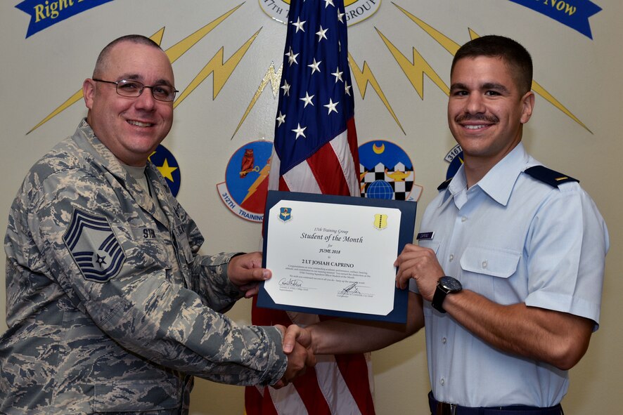 U.S. Air Force Chief Master Sgt. Daniel Stein, 17th Training Group superintendent, presents the 315th Training Squadron Officer Student of the Month award to 2nd Lt. Josiah Caprino, 315th TRS trainee, at Brandenburg Hall on Goodfellow Air Force Base, Texas, July 6, 2018. The 315th TRS’s vision is to develop combat-ready intelligence, surveillance and reconnaissance professionals and promote an innovative squadron culture and identity unmatched across the U.S. Air Force. (U.S. Air Force photo by Senior Airman Randall Moose/Released)