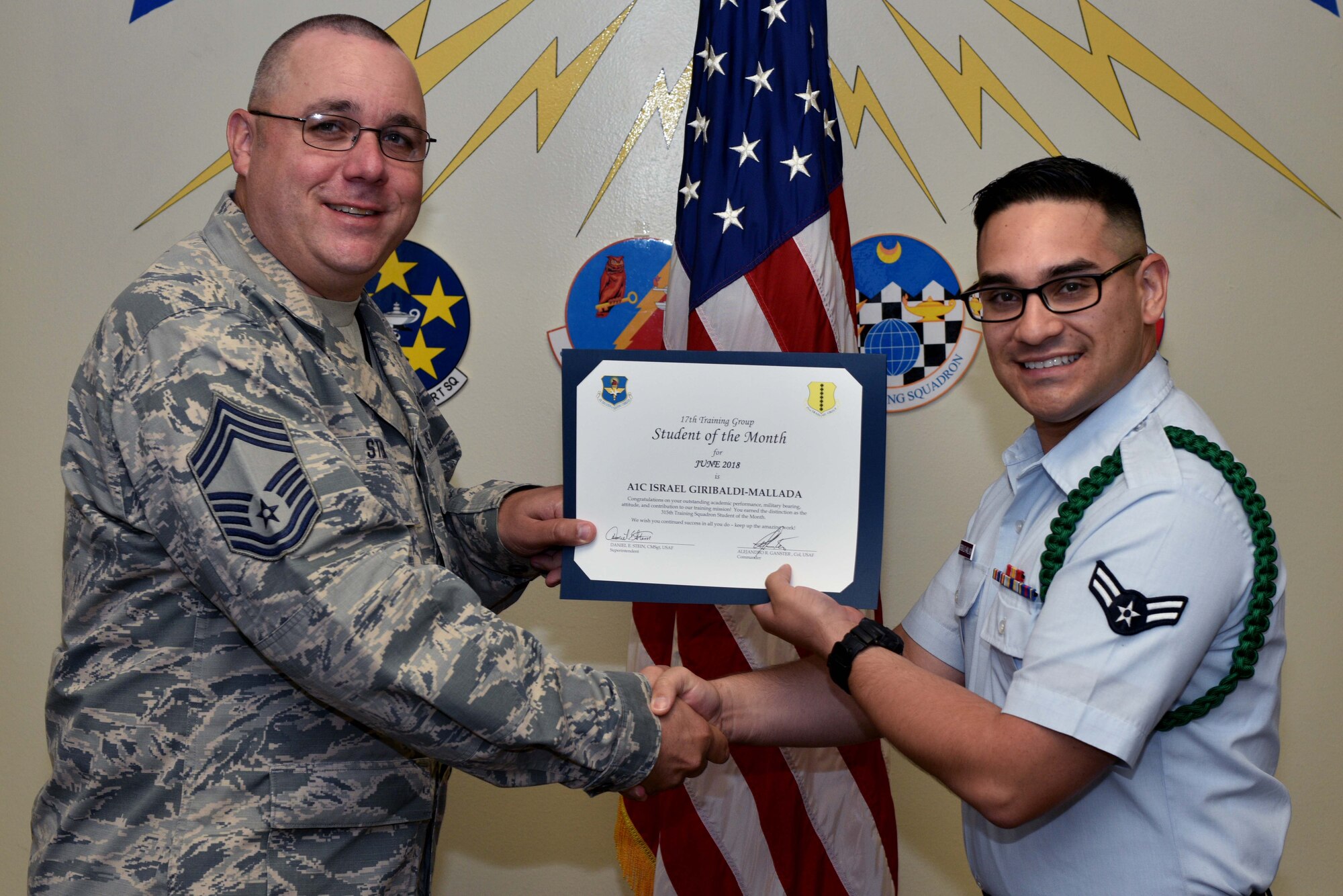 U.S. Air Force Chief Master Sgt. Daniel Stein, 17th Training Group superintendent, presents the 315th Training Squadron Student of the Month award to Airman 1st Class Israel Giribaldi-Mallada, 316th TRS trainee, at Brandenburg Hall on Goodfellow Air Force Base, Texas, July 6, 2018. The 315th TRS’s vision is to develop combat-ready intelligence, surveillance and reconnaissance professionals and promote an innovative squadron culture and identity unmatched across the U.S. Air Force. (U.S. Air Force photo by Senior Airman Randall Moose/Released)