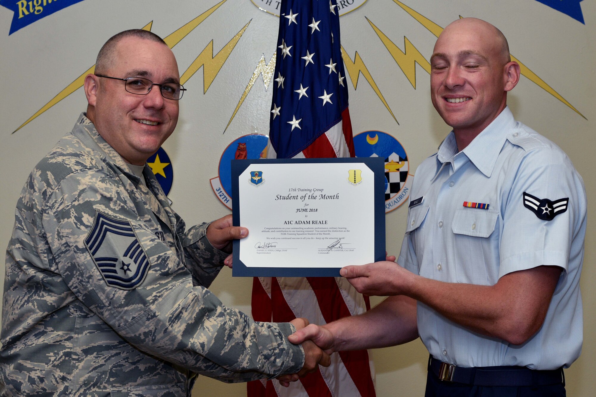 U.S. Air Force Chief Master Sgt. Daniel Stein, 17th Training Group superintendent, presents the 312th Training Squadron Student of the Month award to Airman 1st Class Adam Reale, 312th TRS trainee, at Brandenburg Hall on Goodfellow Air Force Base, Texas, July 6, 2018. The 312th TRS’s mission is to provide Department of Defense and international customers with mission ready fire protection and special instruments graduates and provide mission support for the Air Force Technical Applications Center. (U.S. Air Force photo by Senior Airman Randall Moose/Released)