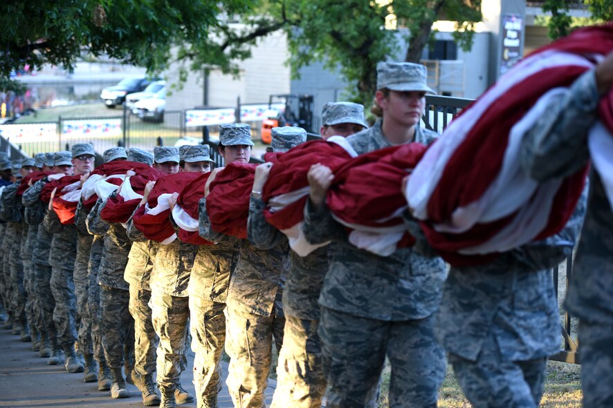 Goodfellow Air Force Base volunteers carry the flag to Chadbourne Street bridge in preparation for the 31st Annual San Angelo Symphony Pops Concert on July 3, 2018, at the Bill Aylor Sr. Memorial RiverStage, San Angelo, Texas. The flag was draped over the bridge while the symphony played ‘The Overture of 1812’ cannon fire from the Old Fort Concho cannon. (U.S. Air Force photo by Airman 1st Class Seraiah Hines/Released)