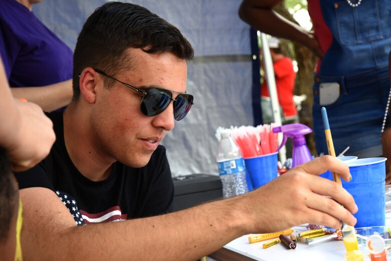 Brian Rivera, Independence Day celebration volunteer, paints faces at the Independence Day celebration on Goodfellow Air Force Base Recreation Camp, Texas, July 4, 2018. After enjoying live music, food and games, attendees could sit on the lake and watch a fireworks display. (U.S. Air Force photo by Airman 1st Class Seraiah Hines/Released)