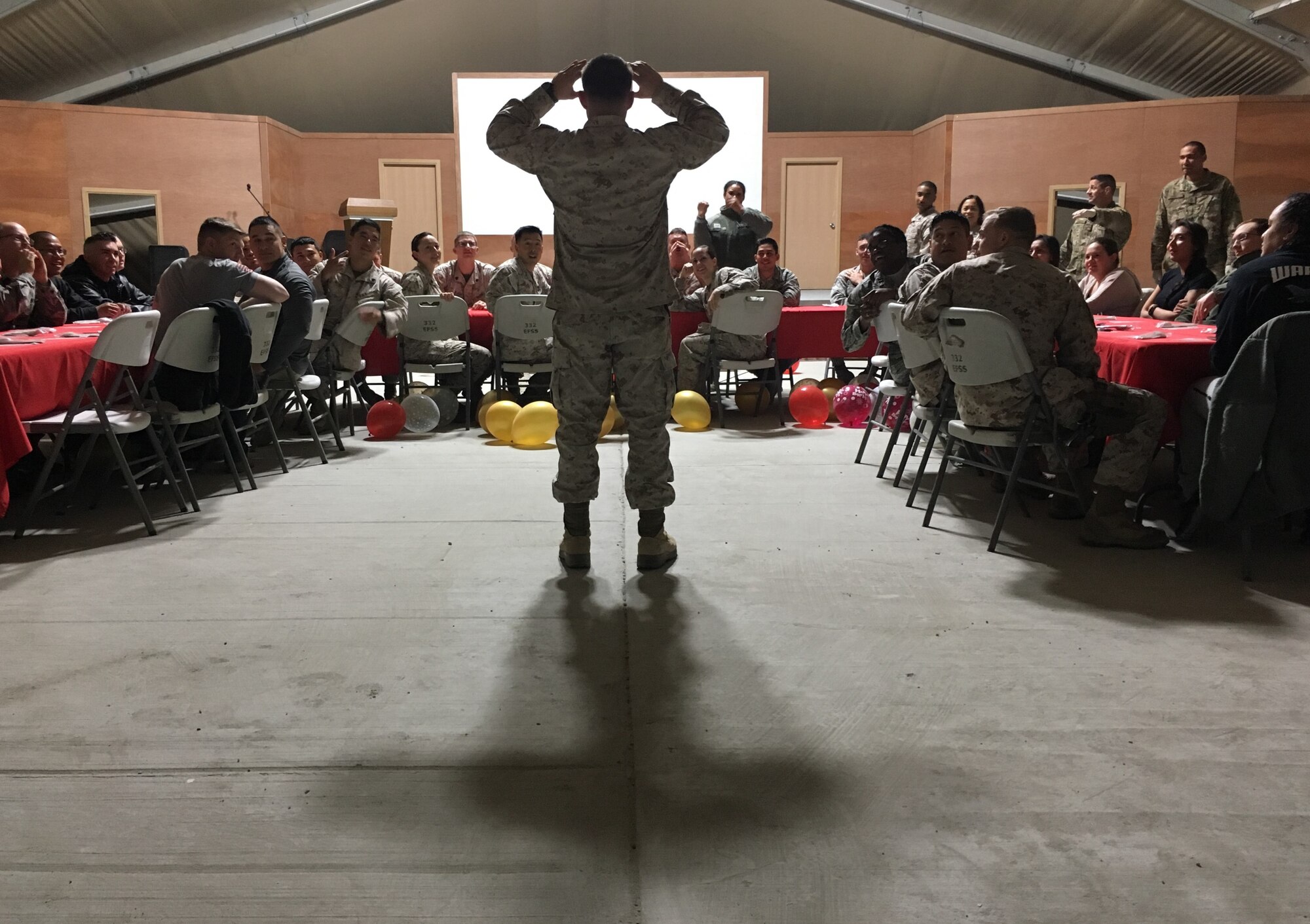 A U.S. Marine attempts to guess a mystery word, through clues given by his brothers and sisters-in-arms, during a monthly birthday celebration, 18 February 2017. Dinners such as these are often part of morale boosting events, while members serve in overseas locations.