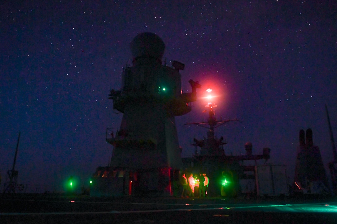 People walk onto the deck of a ship at night.