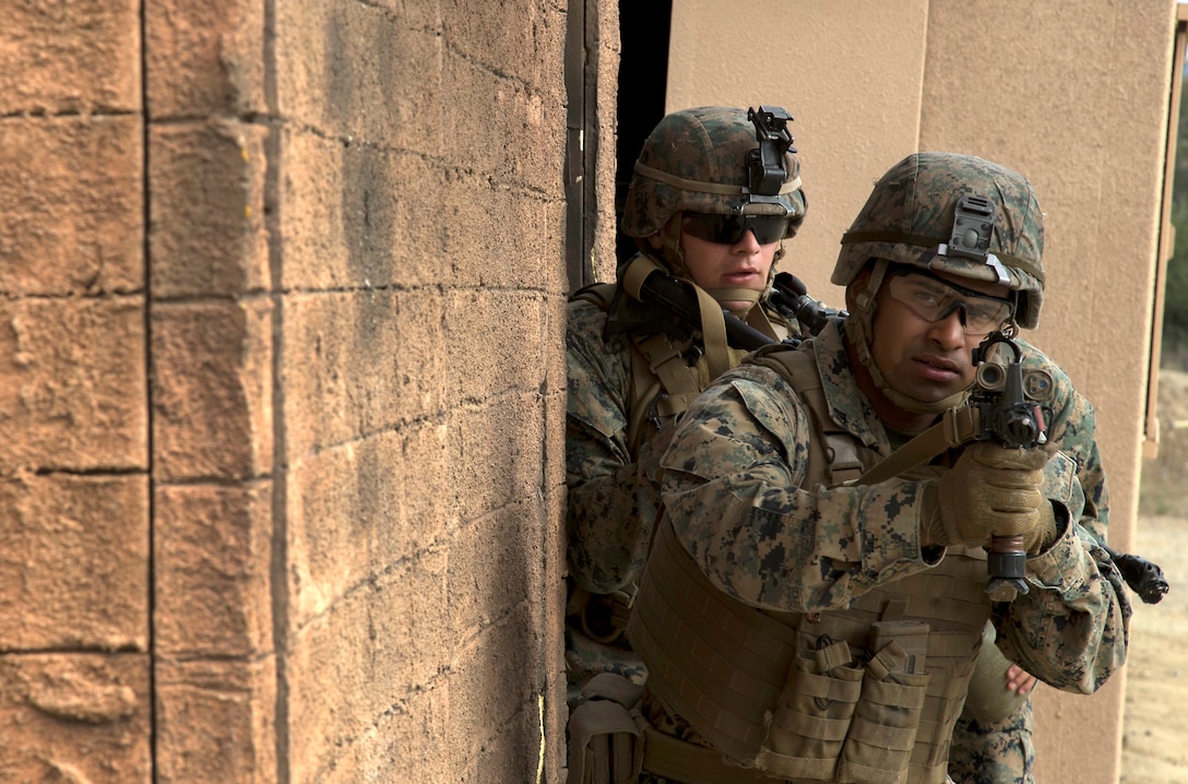 Two Marines come out of a building.