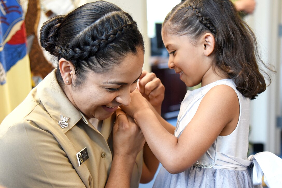 A child places a pin on her mother's uniform.