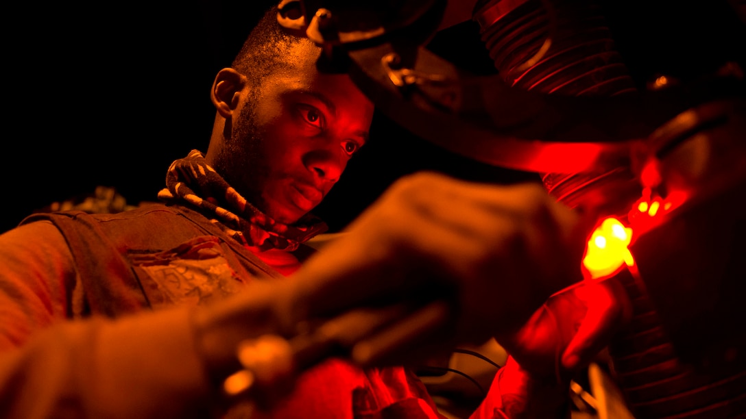 A sailor is illuminated by red light.