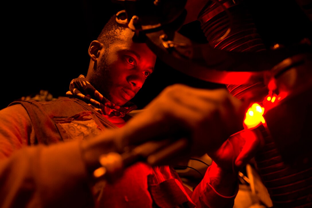 A sailor is illuminated by red light.