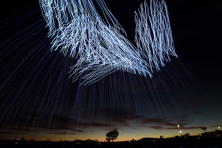 Streaks of light show in the sky above a strip of light from the sunset.