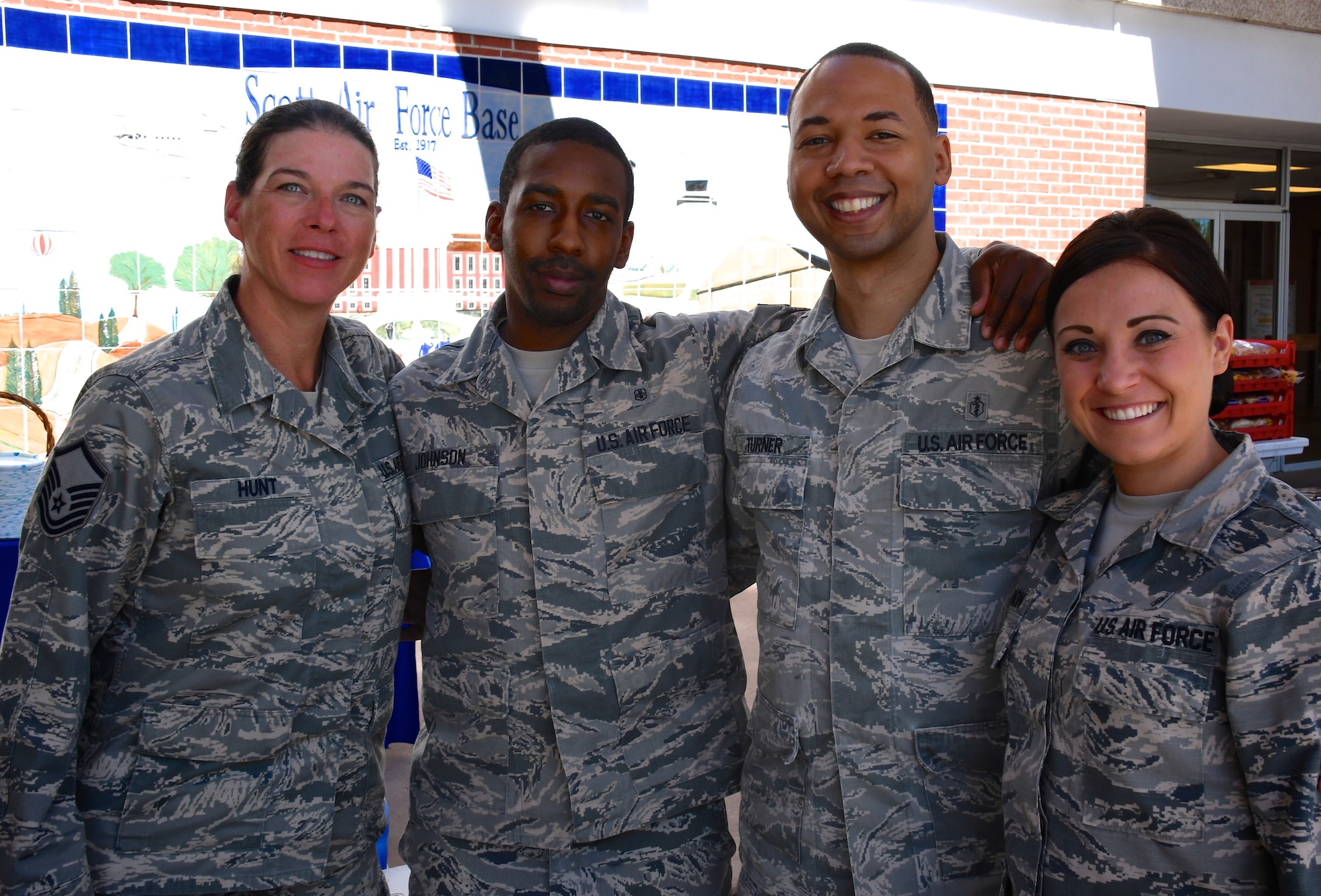 Master Sgt. Denise Hunt, the career advisor for the 932nd Aeromedical Staging Squadron, welcomes back two deployers including Senior Airman Dominique Johnson (second from left) and Staff Sgt. Kristine Cannon (far right) with assistance from Master Sgt. Tray Turner (second from right) during a special "welcome home" luncheon July 7, 2018, at Scott Air Force Base, Ill.  The USO of Missouri came out and provided pulled pork as part of the lunch along with a cake.  (U.S. Air Force photo by Lt. Col. Stan Paregien)