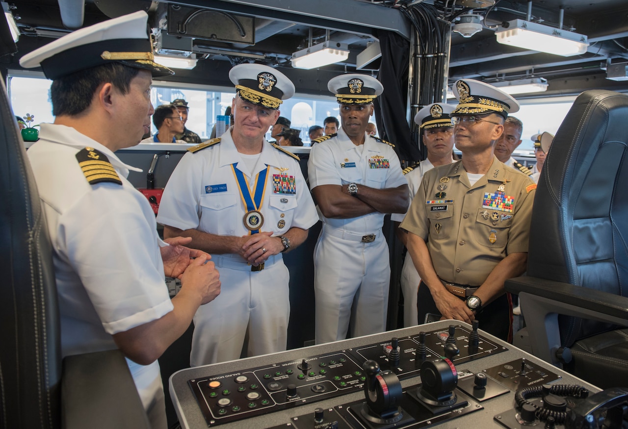 Naval officers talk on ship's bridge.