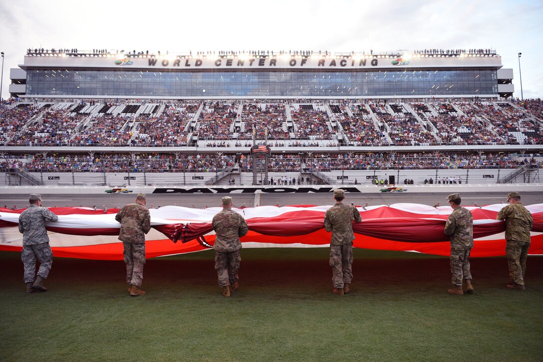 Service members gather a flag they unfurled July 7, at the Daytona International Speedway in Daytona Beach, Fla. The unfurling was part of the pre-race ceremonies for the Daytona Coke Zero Sugar 400 and NASCAR Salutes – NASCAR's recognition and honor of military members. (U.S. Air Force photo by Airman 1st Class Zoe Thacker)