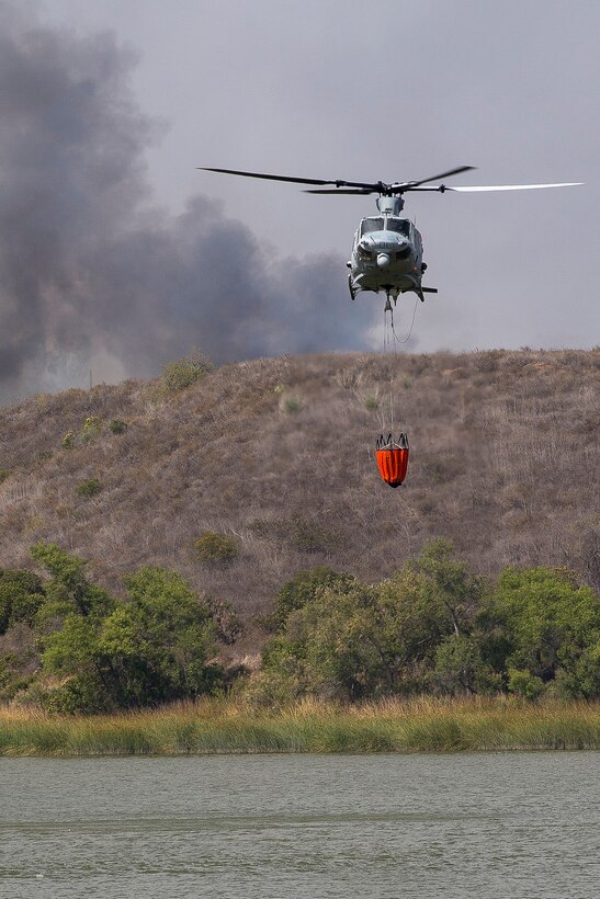 A Marine Corps helicopter refills a bucket firefighting system in Lake O'Neill while on a firefighting mission.