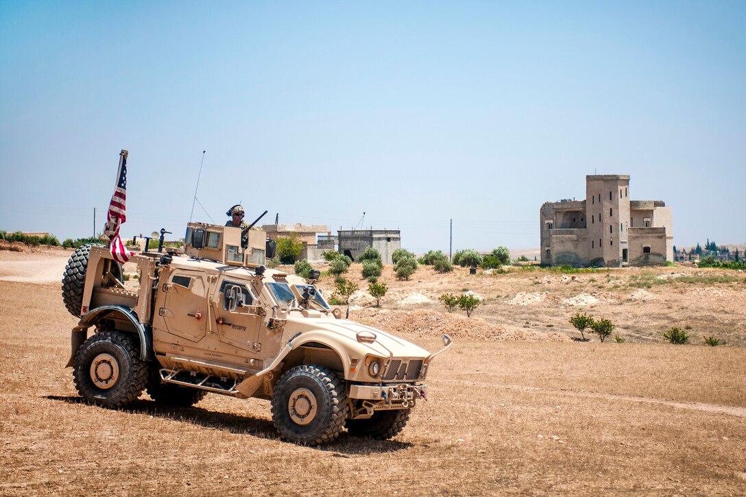 Soldiers drive their tactical vehicle through a blockade.
