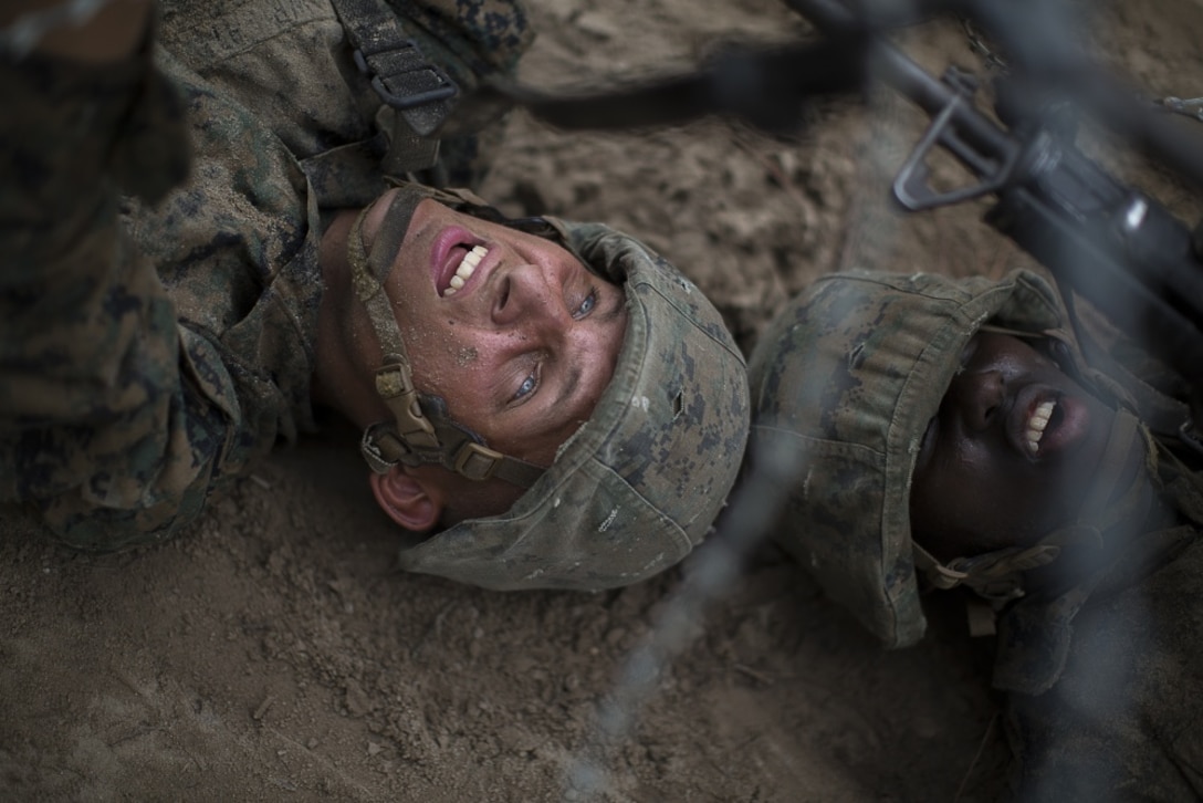 U.S. Marine Corps Rct. Douglas Wright, with Platoon 2057, Echo Company, 2nd Recruit Training Battalion, lifts a concertina wire so that his fireteam partner, Rct. Jovan Jones, with Platoon 2057, Echo Company, 2nd Recruit Training Battalion, can crawl underneath during Basic Warrior Training July 6, 2018 on Parris Island, S.C. Basic Warrior Training is designed to teach the importance of teamwork, working under stress and how to perform well while utilizing small unit leadership. Echo Company is scheduled to graduate Aug. 14, 2018. Approximately 19,000 recruits come to Parris Island annually for the chance to become United States Marines by enduring 12 weeks of rigorous, transformative training. Parris Island is home to entry-level enlisted training for 49 percent of male recruits and 100 percent of female recruits in the Marine Corps.