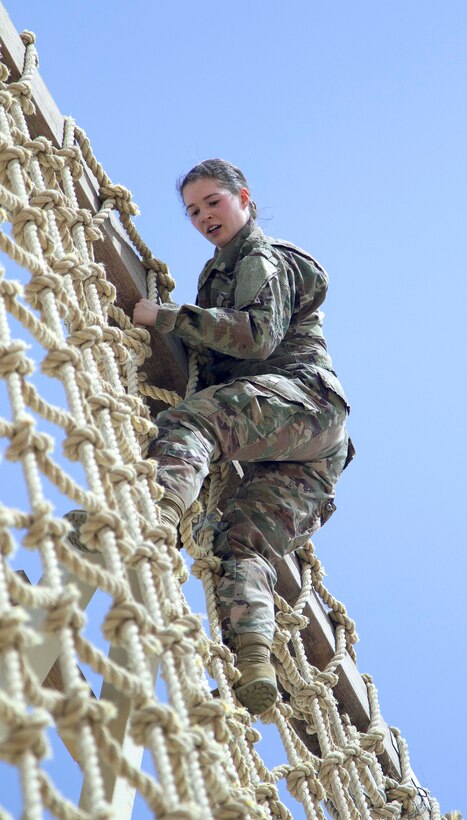A soldier climbs down a high rope wall obstacle.