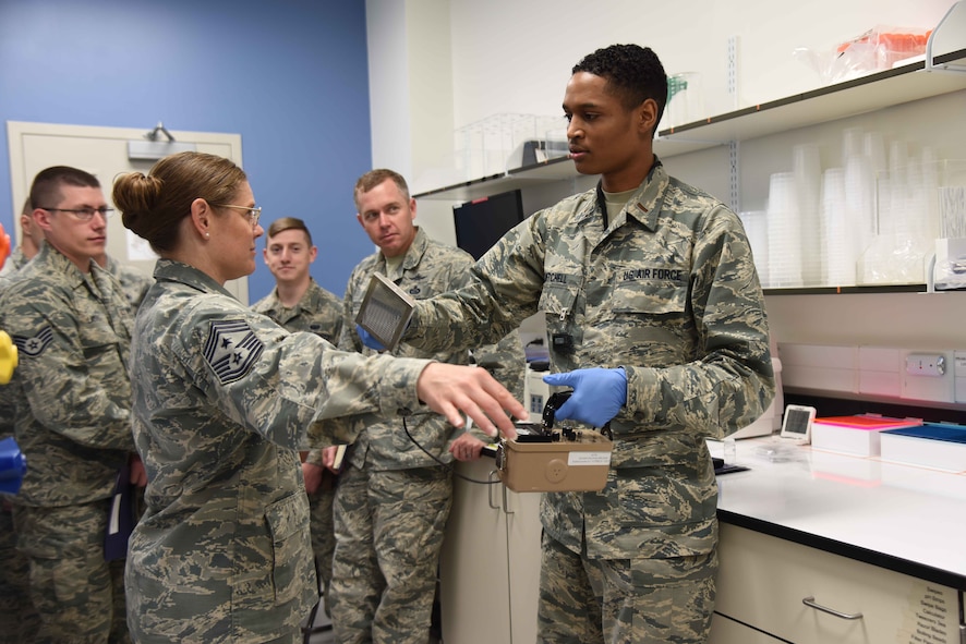 2nd Lt. Kaleb Mitchell, a chemist at the Air Force Radiochemistry Lab at Patrick AFB, Fla., checks Chief Master Sgt. Jessica Bender, command chief for the 9th Reconnaissance Wing, Beale AFB, Calif., for possible radioactive contamination using a hand-held radiation monitor.  Bender was one of 35 Airmen within 25th Air Force who visited DoD's sole nuclear treaty monitoring center June 1, 2018 to learn more about AFTAC's innovative mission.  (U.S. Air Force photo by Susan A. Romano)