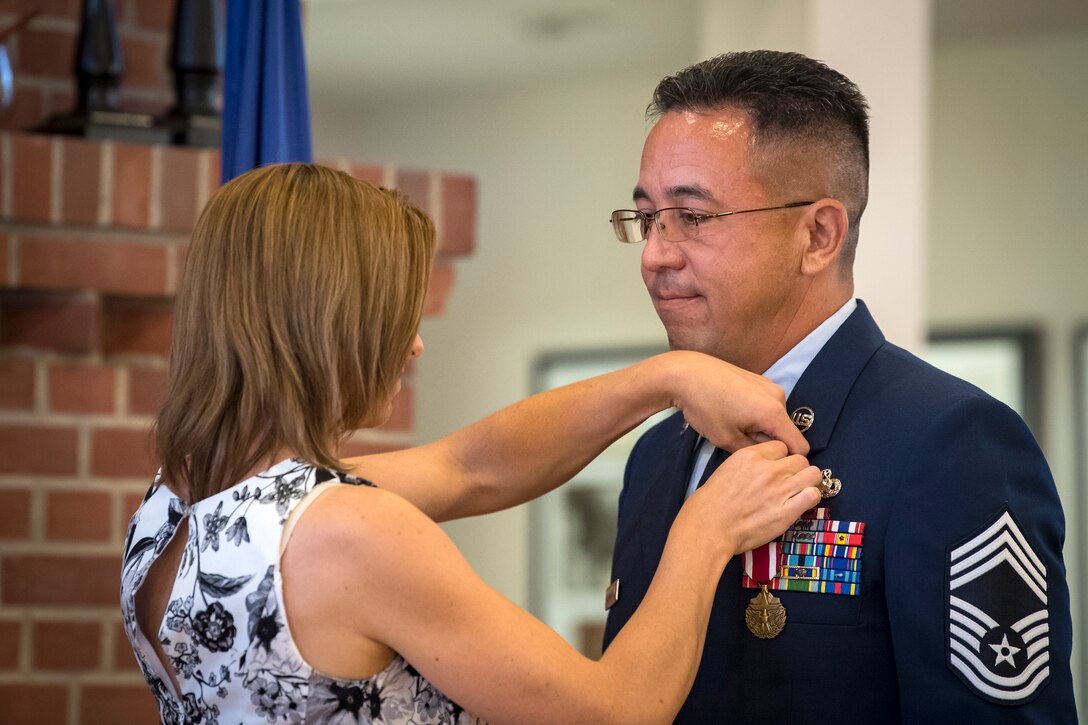 Jill Banghart, places a retirement pin on her spouse, Chief Master Sgt. Jay Banghart, 23d Maintenance Squadron operations chief, July 6, 2018, at Moody Air Force Base, Ga. Banghart entered the Air Force in 1990 and served in numerous positions within the aircraft maintenance career field throughout his 28 year Air Force career. (U.S. Air Force photo by Airman 1st Class Eugene Oliver)