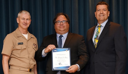 IMAGE: Vice Adm. Thomas Moore, commander of Naval Sea Systems Command (NAVSEA), and James Smerchansky, NAVSEA Executive Director, presented a Scientific and Professional Executive Award to NSWCDD engineer Dr. George Foster at a NAVSEA headquarters ceremony, June 18. 

As the Distinguished Engineer for Combat Control, Foster is the Navy's expert in the technical area of combat systems and leads research in the basic scientific principles and technology trends in the combat control domain. Foster led efforts to integrate electronic warfare into the combat system through the re-architecture of the Electronic Warfare System, leveraging the efforts of multiple Future Naval Capability research programs to develop an open system that allows for easier integration of new decoys and effectors. He advanced this effort further in 2016 when he took leadership of the Surface Navy's effort in force-level engagement coordination.