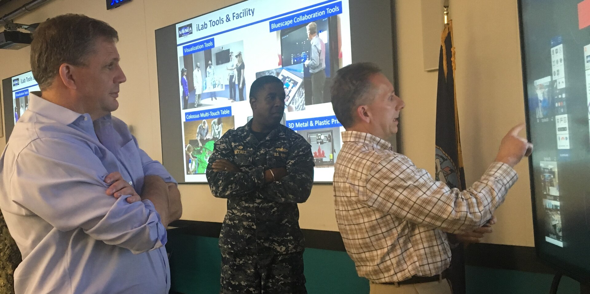 IMAGE: DAHLGREN, Va. (June 28, 2018) - Naval Surface Warfare Center Dahlgren Division (NSWCDD) Chief Innovation Officer Nelson Mills demonstrates the Bluescape collaboration software for James Geurts, Assistant Secretary of the Navy for Research for Development and Acquisition, during his tour of the NSWCDD Innovation Lab (iLab). NSWCDD Commanding Officer Capt. Godfrey 'Gus' Weekes looks on as Mills explains how the virtual workspace allows for real-time cloud-based collaboration. Virtualization and directed energy were among the briefs NSWCDD scientists and engineers presented to Geurts who also observed a laser demonstration. As the Navy's acquisition executive, Geurts has oversight of an annual budget in excess of $60 billion and is responsible for equipping and supporting Sailors and Marines with the best platforms, systems and technology as they operate around the globe in defense of the nation.