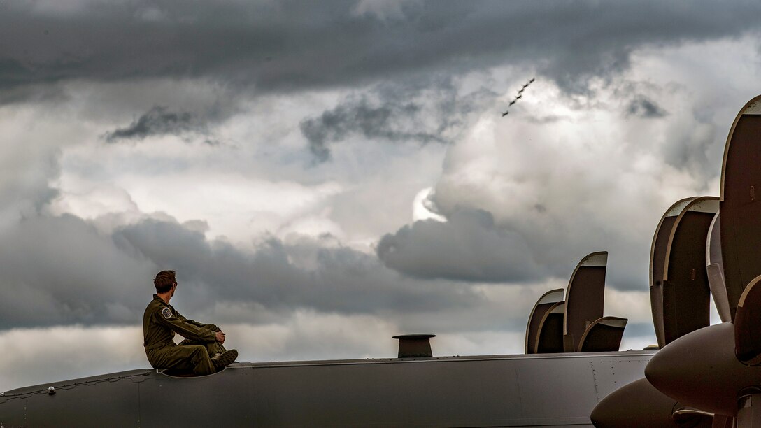 A pilot sits on top of an aircraft while watching an aircraft performance.