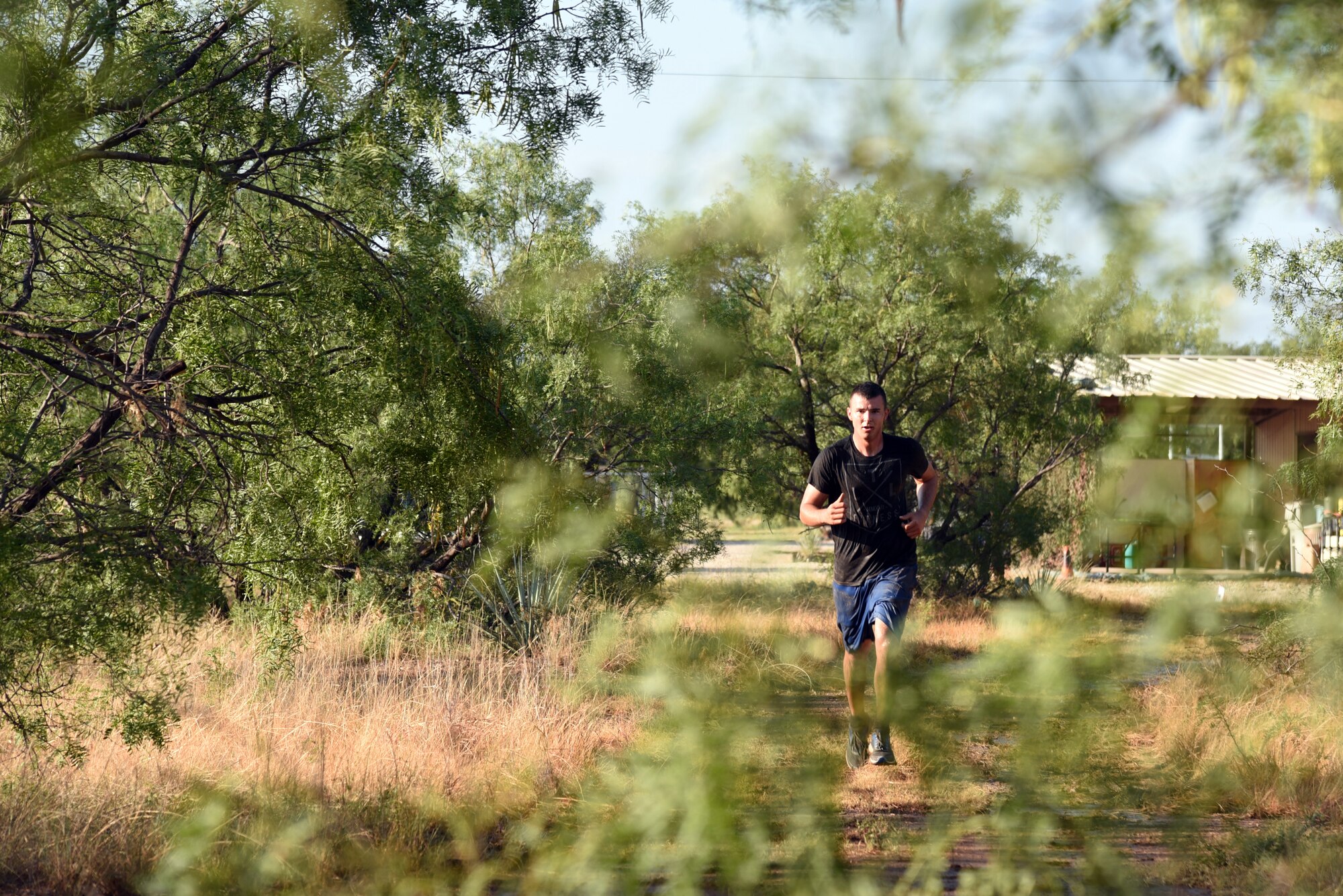 U.S. Army Pvt. Conner McCage, 344th Military Intelligence Battalion trainee, runs through a wooded area during the 344th MI BN mud run near the Camp Sentinel training area on Goodfellow Air Force Base, Texas, July 7, 2018. The mud run consisted of a 2.2 mile course and featured several obstacles. (U.S. Air Force photo by Staff Sgt. Joshua Edwards/Released)
